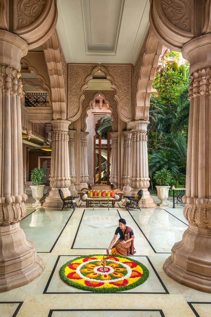 Carved stone colonnade over polished marble flooring with a floral rangoli at a Sage Thread space in Bangalore